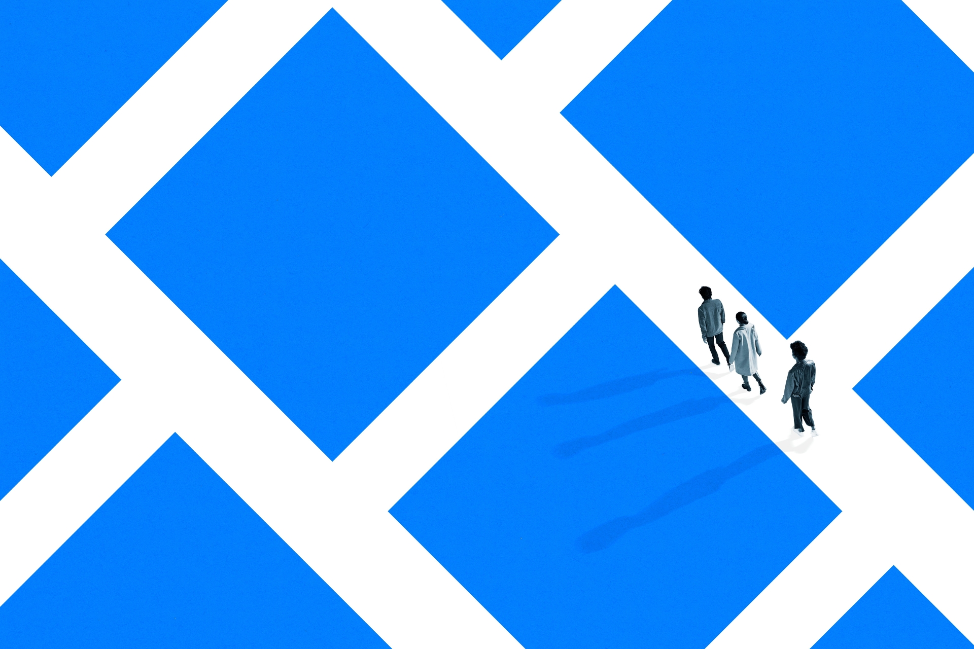 Three young adults walking through a maze of blue blocks.